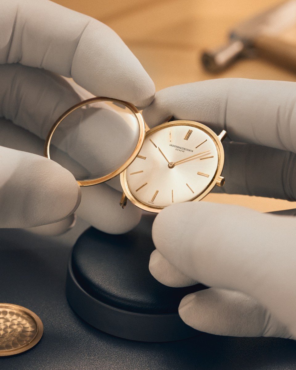  Gloved hands assembling a classic Vacheron Constantin watch with a white dial.