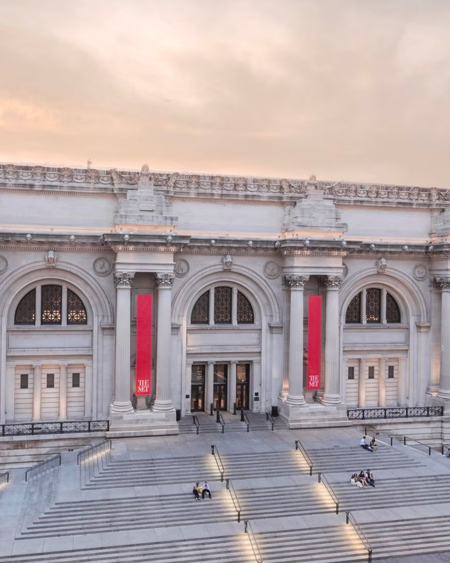 Front entrance of  The Met with red banners and classical architecture.