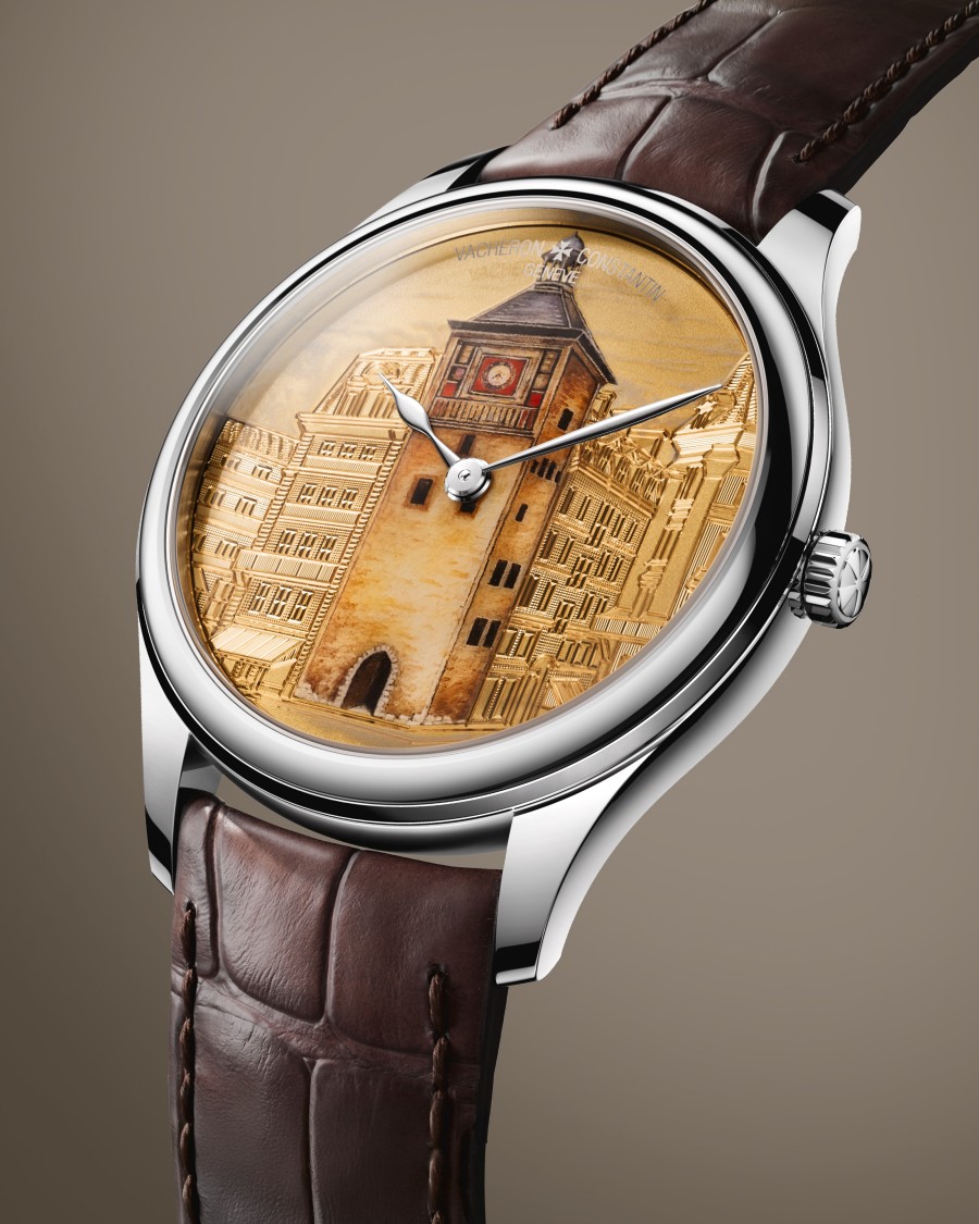 An elegant wristwatch with a brown leather strap, silver case, and an engraved architectural design on the dial.