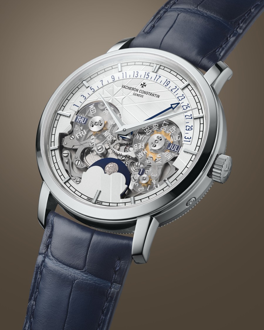 A stylish watch with a blue leather strap, silver case, transparent dial showcasing the mechanical movement, and additional sub-dials.