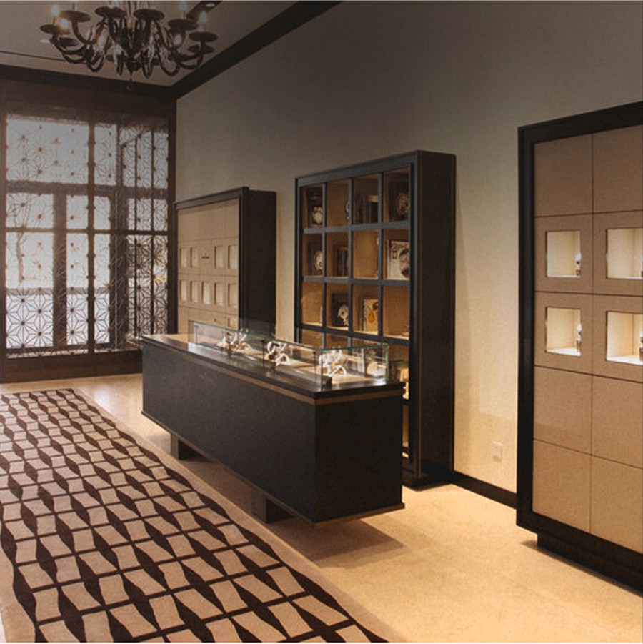 Interior of a luxury watch boutique with display counters, illuminated shelves, and large windows.