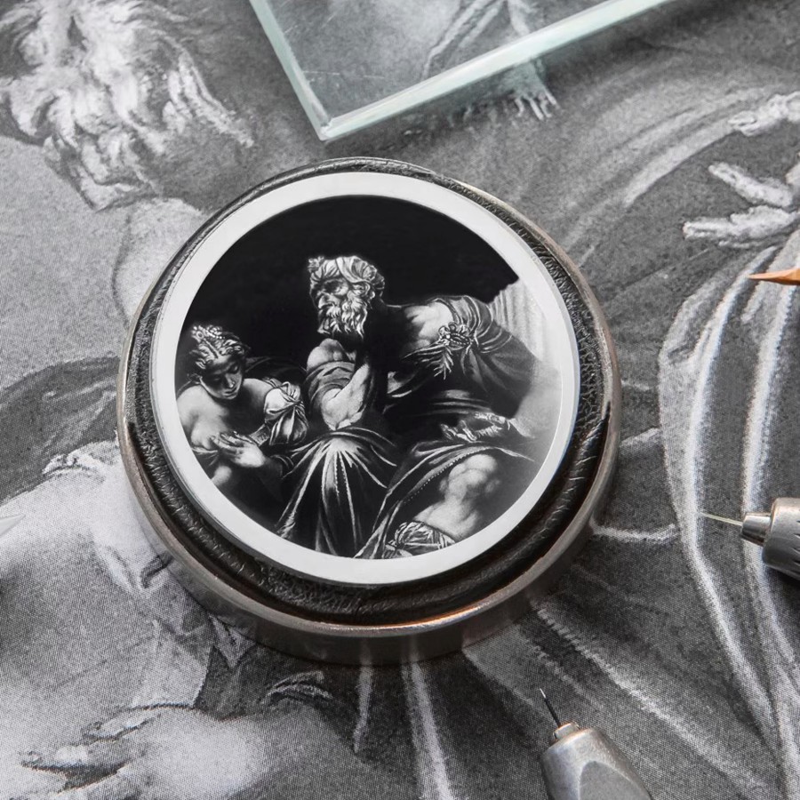 A detailed engraving on a circular metal object depicts a bearded man seated and a woman beside him.