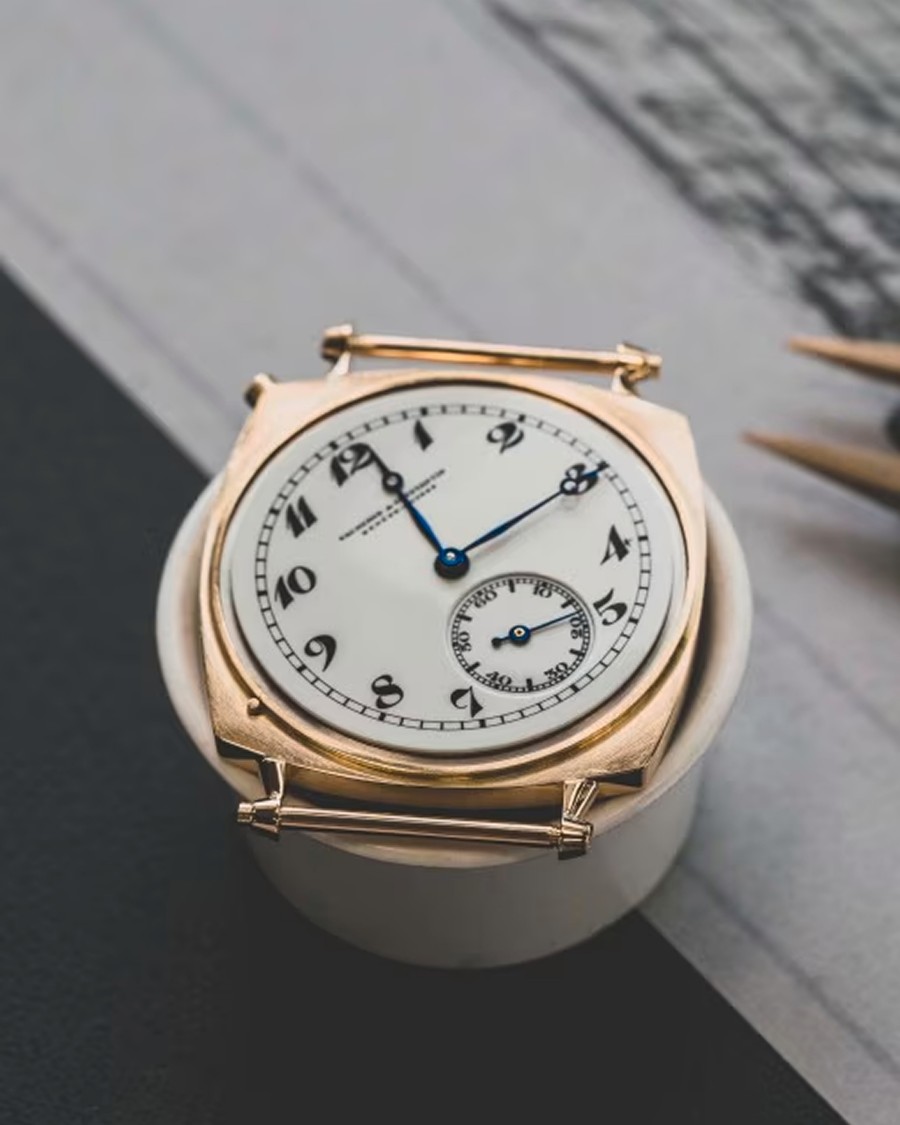 Top view of a vintage-style Vacheron Constantin watch with a white dial, black numerals, and small seconds subdial, placed on a dark surface.