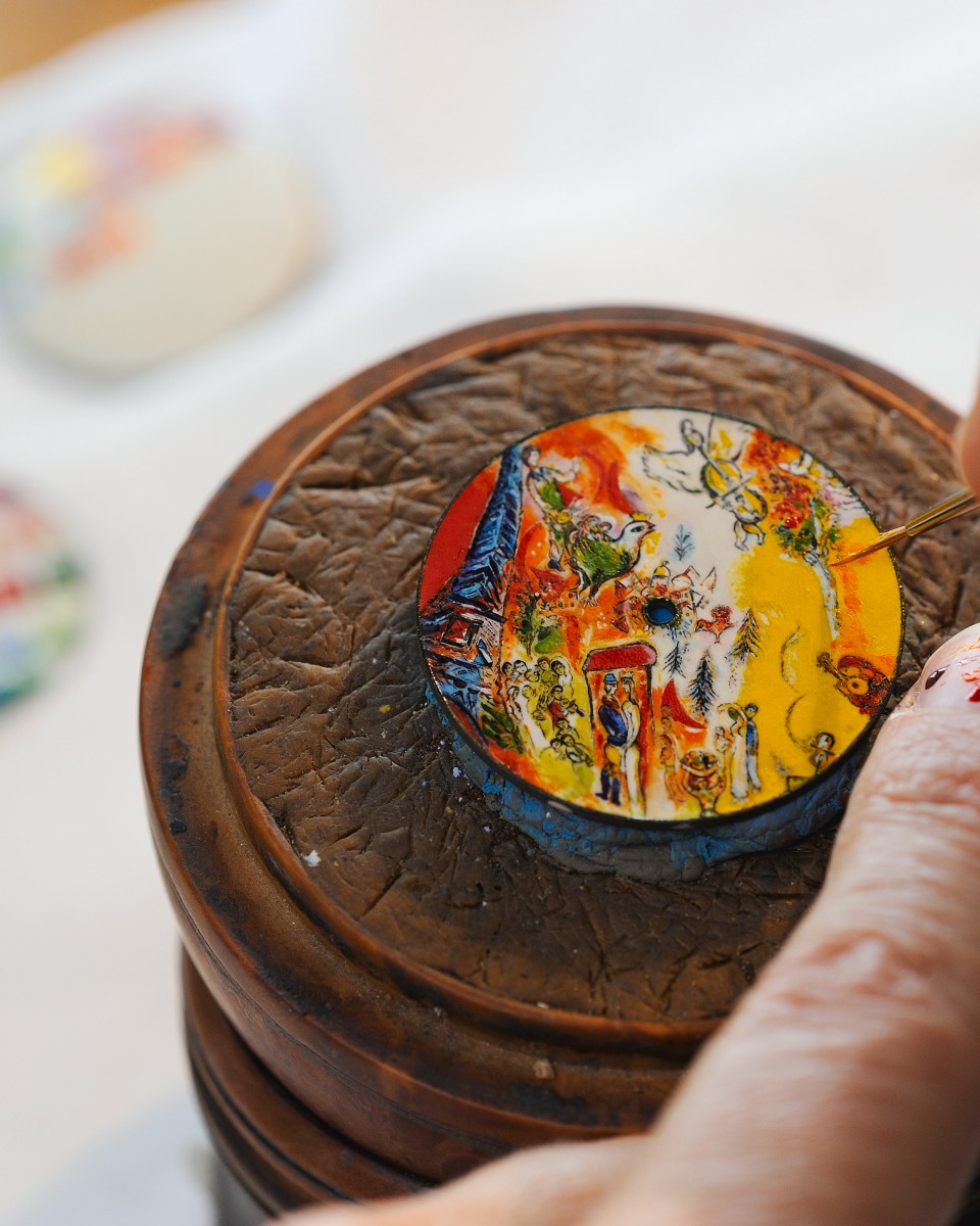  Miniature painted watch dial with a vivid countryside  scene in yellow and red tones.