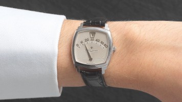 A woman's wrist wearing a watch with a black leather strap and a silver face.