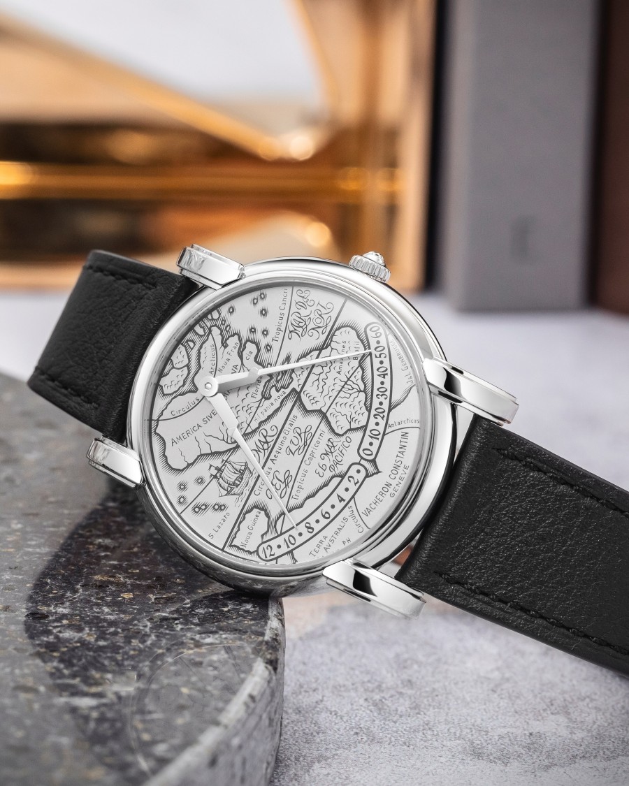 A watch with a round case, silver details,  and a black leather strap.