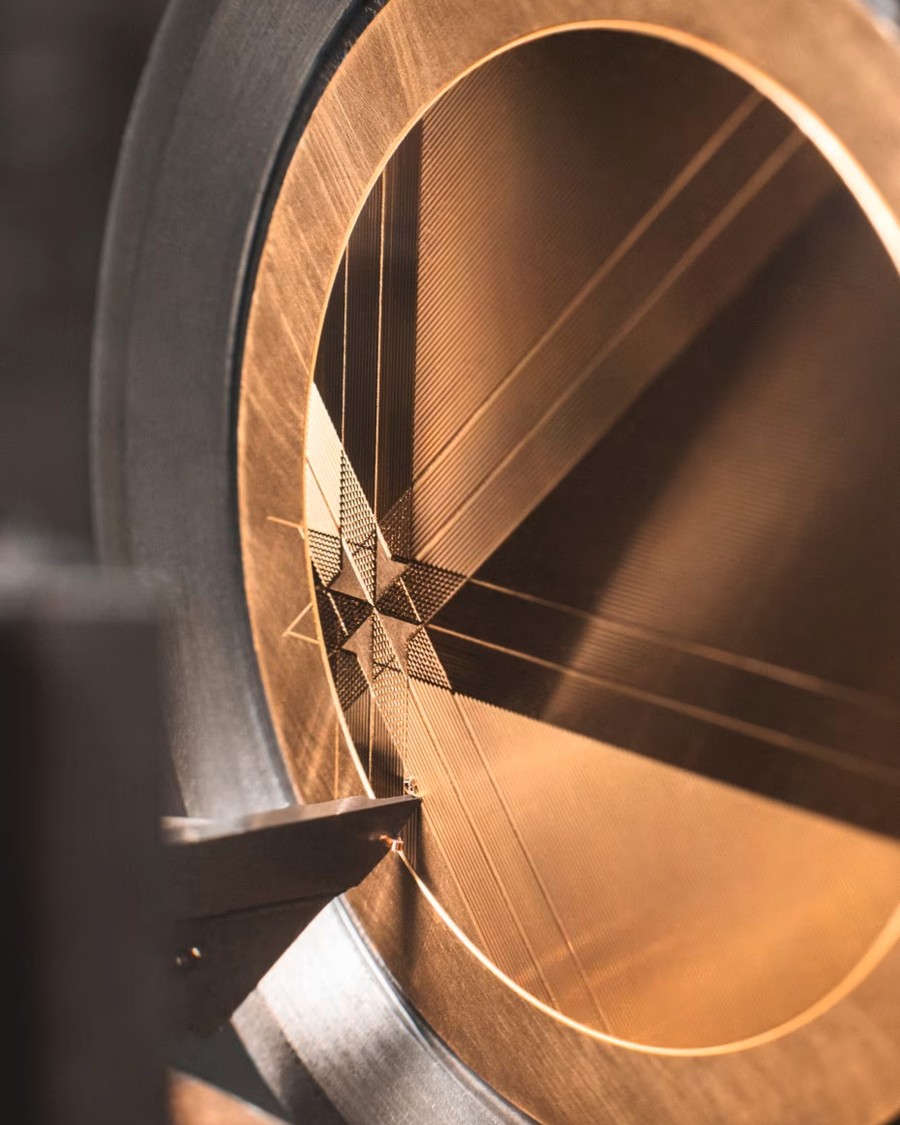 Engraving process on a gold watch dial with intricate geometric patterns.