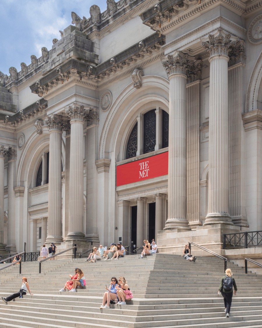 Front view of the Met museum with people seating on the stairs