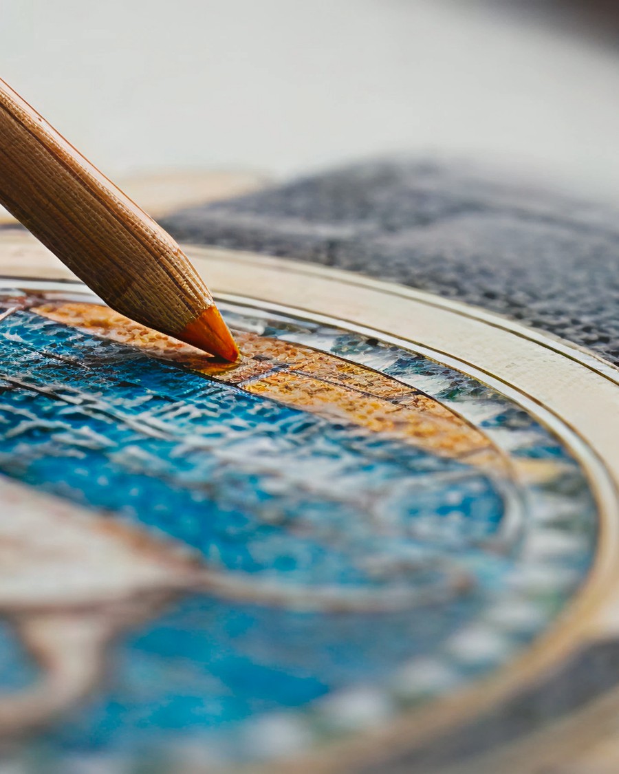 Detailed view of a hand painting blue and gold details on a watch dial using a fine brush.